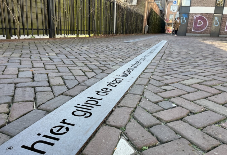 Het straatgedicht Hier glipt de stad tussen zichzelf door in de klimaatstraat.